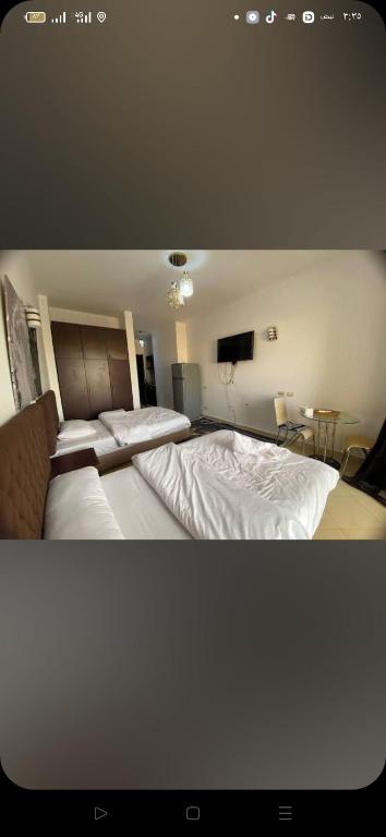 Un dormitorio con dos camas y un televisor. en فلورينزا الخمسين, en Hurghada