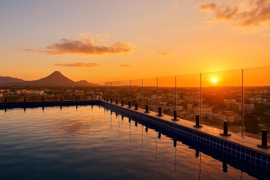 a swimming pool with the sunset in the background at Suite Sky and Sea in Flic-en-Flac