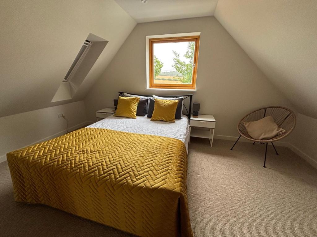 1 dormitorio con 1 cama con sábanas amarillas y ventana en Tranquil Pond View Loft Retreat in Sudbury, en Bulmer