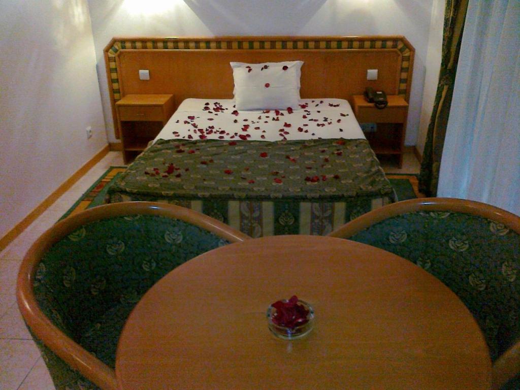 a small room with a bed and a table with a table sidx sidx at Real Caparica Hotel in Costa da Caparica