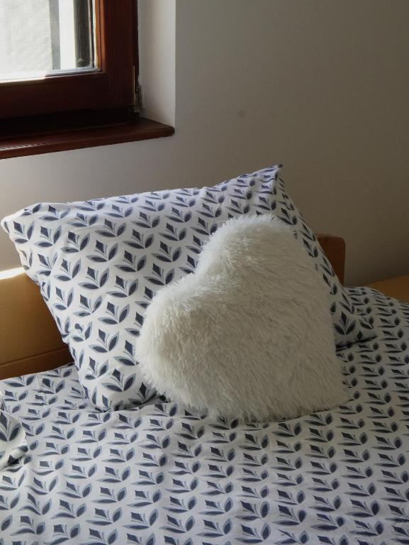 a white pillow sitting on a bed with a blue and white pillow at Plavi apartman Airport in Belgrade