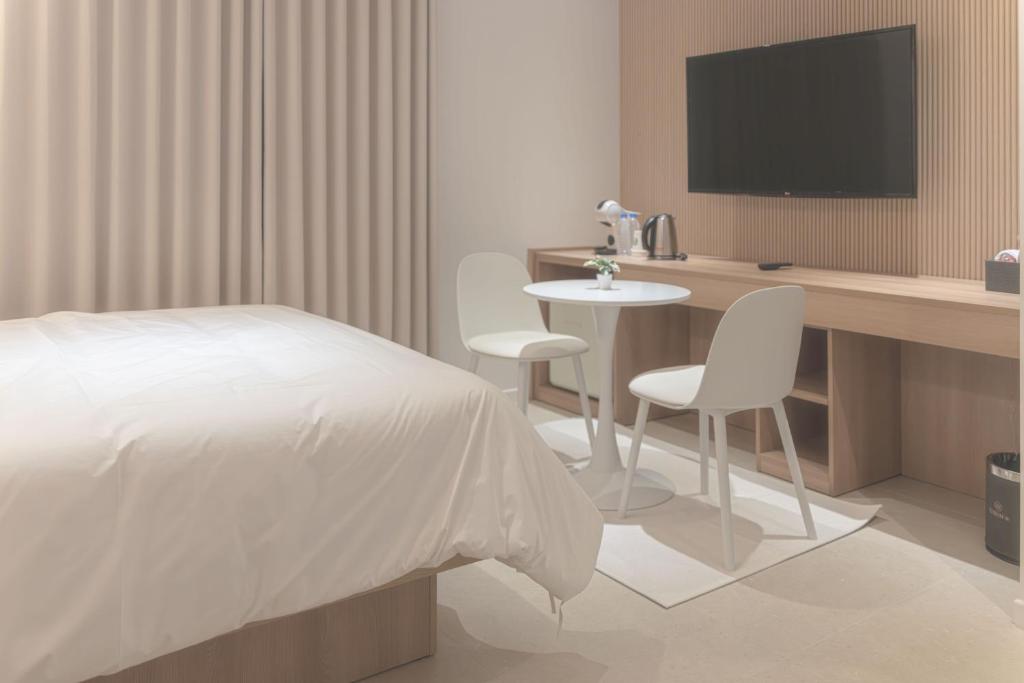 a bedroom with a bed and a desk with a tv at 인별호텔 in Suncheon
