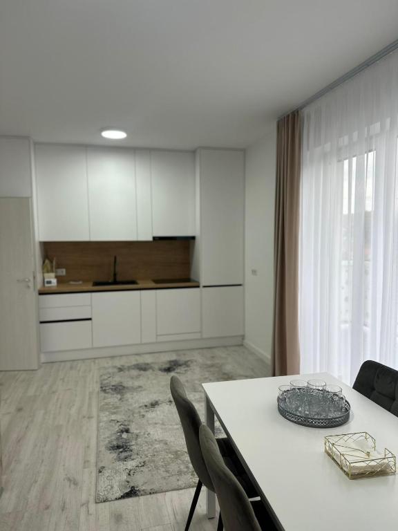 a white kitchen with a white table and chairs at Apartament panoramic in Bistriţa