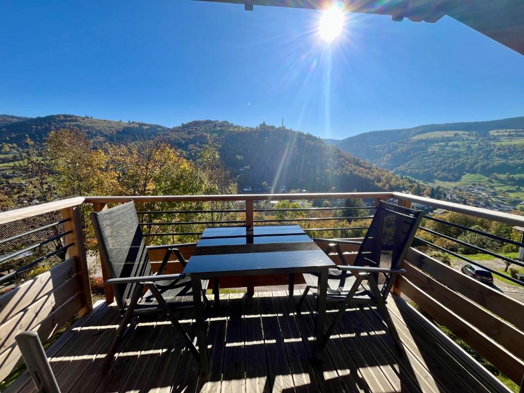 a table and two chairs on a deck with a view at Superbe appartement neuf avec Sauna privé & Terrasse vue sur la montagne in La Bresse