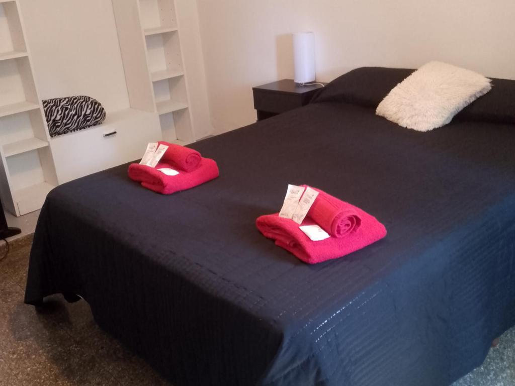 two slippers are sitting on a black bed at Departamento Pablo's in Río Colorado