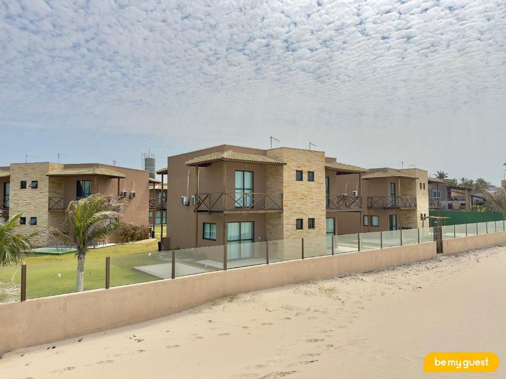 a row of houses on the beach with a fence at Beachfront Duplex B por Be My Guest in Aquiraz