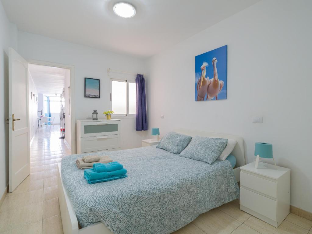 ein Schlafzimmer mit einem Bett mit blauen Kissen darauf in der Unterkunft Pura Vida - 10 min de Maspalomas y Aeropuerto in Vecindario