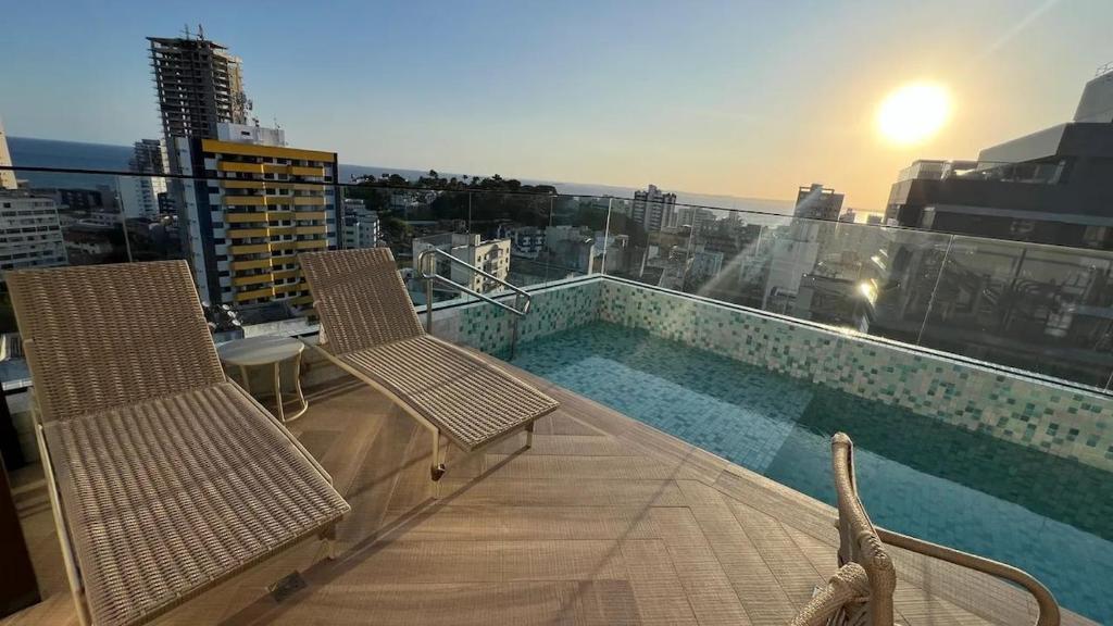 un balcón con 2 sillas y una piscina en un edificio en Studio Barra Salvador -, en Salvador