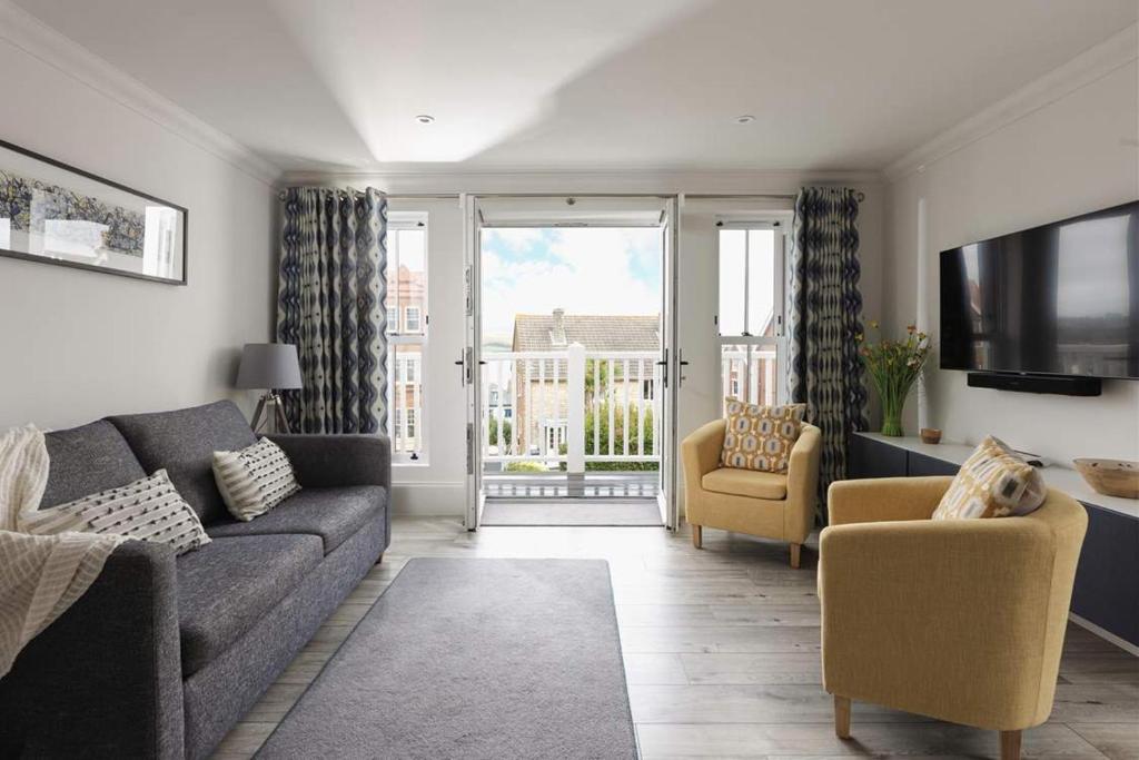 a living room with a couch and chairs and a tv at 5 The Lookout - 2 bed apartment with parking, balcony & sea views in Swanage