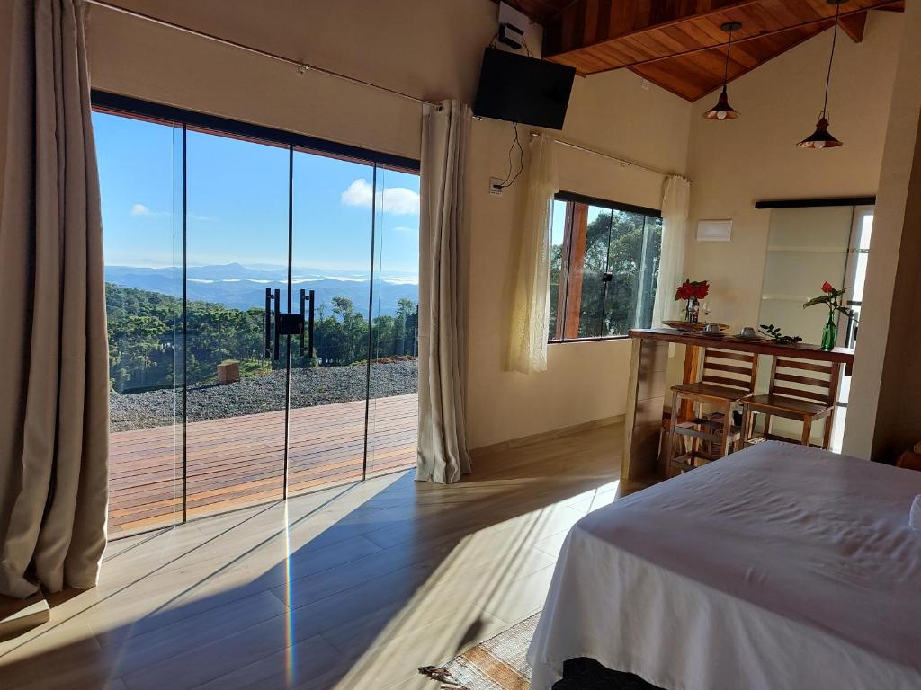 a bedroom with a bed and a large glass window at Chalés Ser Tão di Minas in Paraisópolis