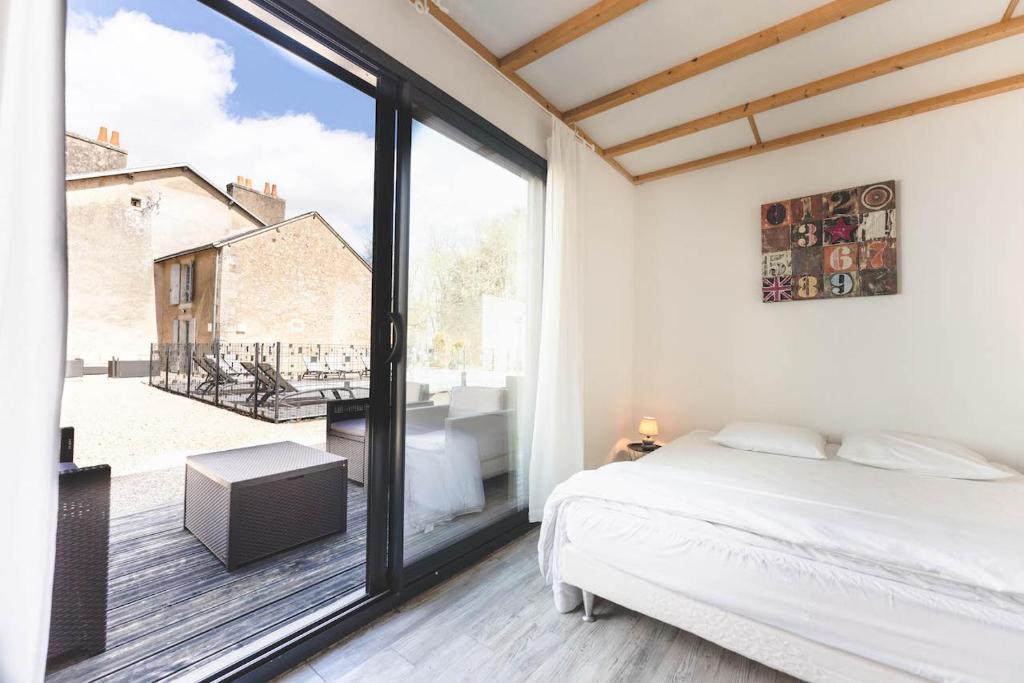 a bedroom with a bed and a large window at Le gite du buis in Montamisé