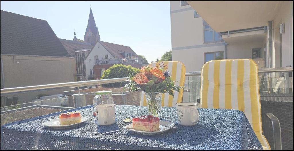 a table with two slices of cake and a vase of flowers at FeWo "Hafenblick" in Barth