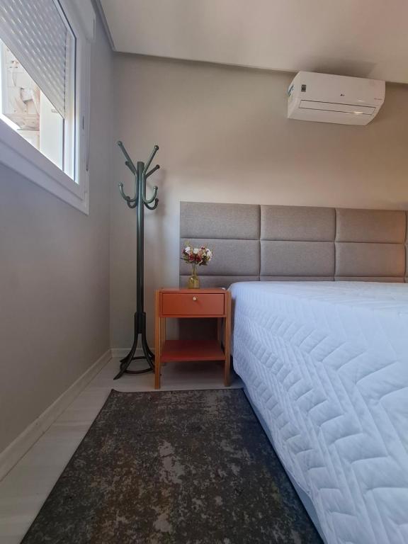 a bedroom with a bed and a table and a window at NOVO e DECORADO no Centro de Canela! in Canela