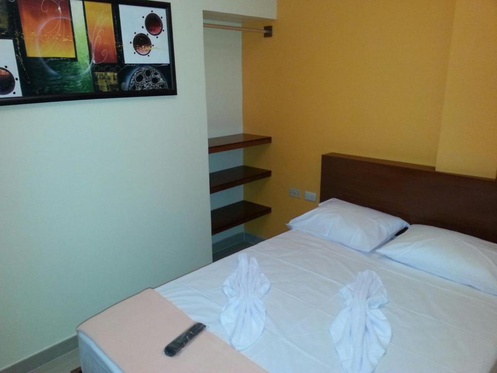 a bedroom with a bed with a remote control on it at Hotel Carrizal Suites in Barinas