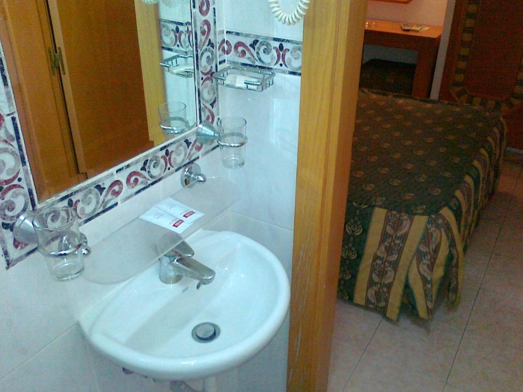 a bathroom with a white sink and a mirror at Real Caparica Hotel in Costa da Caparica