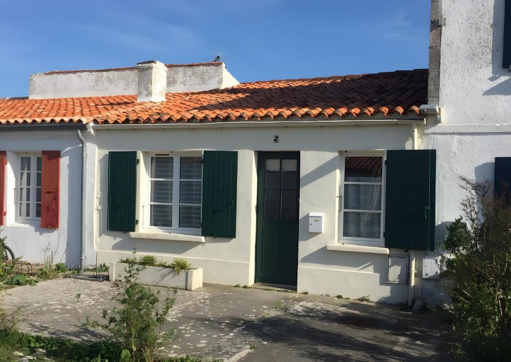 a white house with green shutters and a red roof at Maison de village in Île dʼAix
