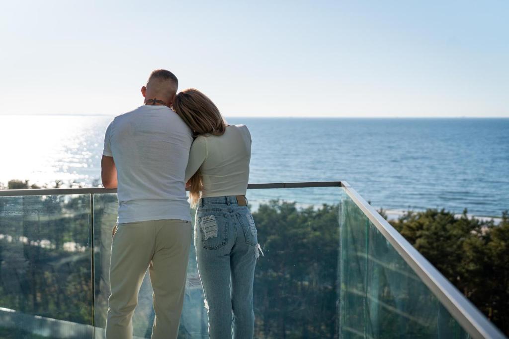 un hombre y una mujer de pie en un balcón con vistas al océano en Wave Holiday Club, en Międzyzdroje