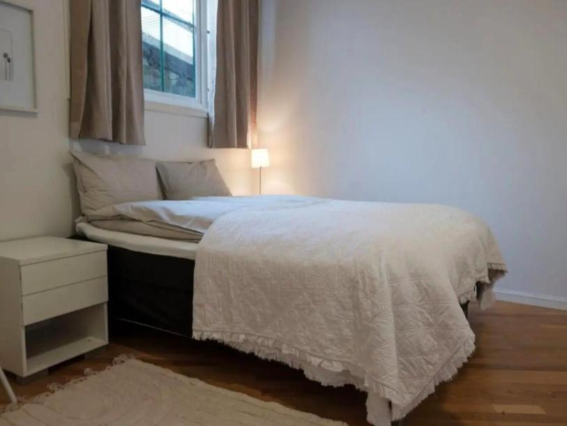 a bedroom with a bed with a white bedspread and a window at Cheap Room in The Heart of Brosundet in Ålesund