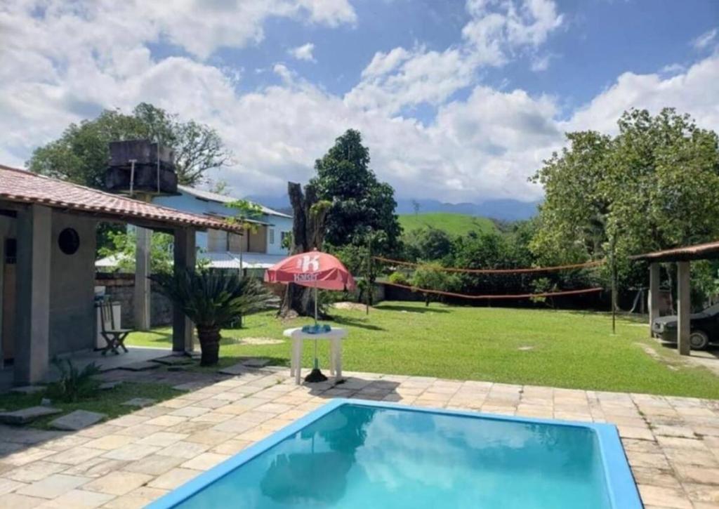 a backyard with a swimming pool and an umbrella at Sítio Serra Verde in Guapimirim