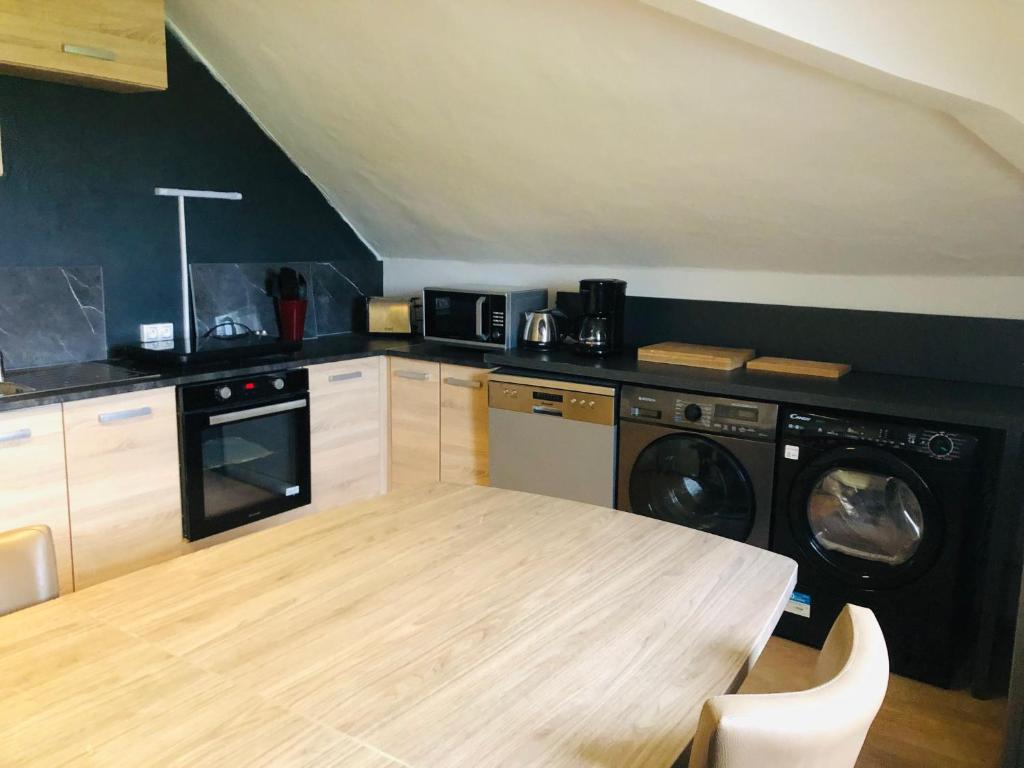 une cuisine avec une table en bois et un lave-linge/sèche-linge dans l'établissement Appartement - LES COMBLES DU CHATEAU DES MARAIS - Avec vue sur le lac - POUR 2 à 5 PERSONNES, à Saint-Philbert-de-Grand-Lieu