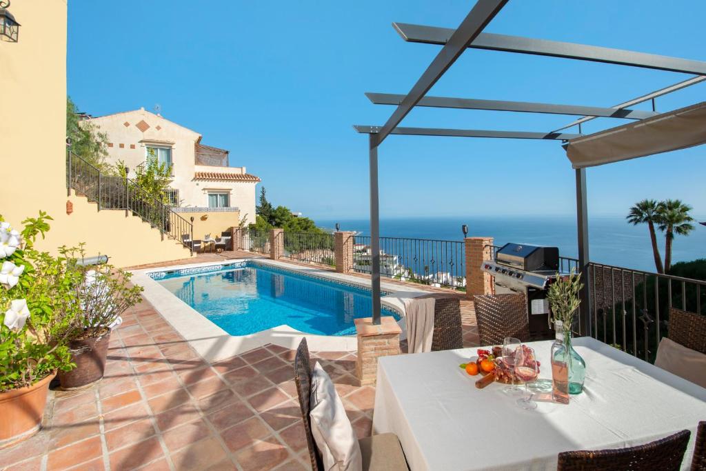 a villa with a swimming pool and a patio with a table at Villa Sol y Mar with heated pool and jacuzzi in Salobreña