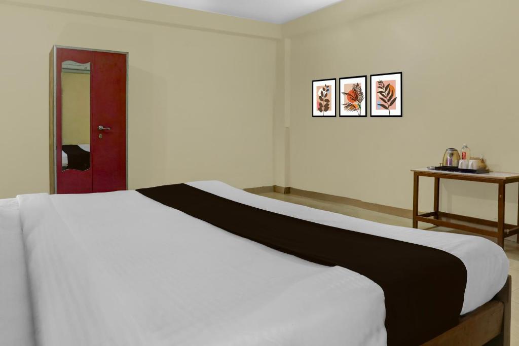 a bedroom with a large white bed and a red door at Hotel O BABA GUEST HOUSE in Shivāpur
