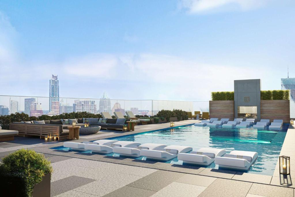 una piscina con tumbonas blancas en la parte superior de un edificio en High Rise in the heart of ATX, en Austin