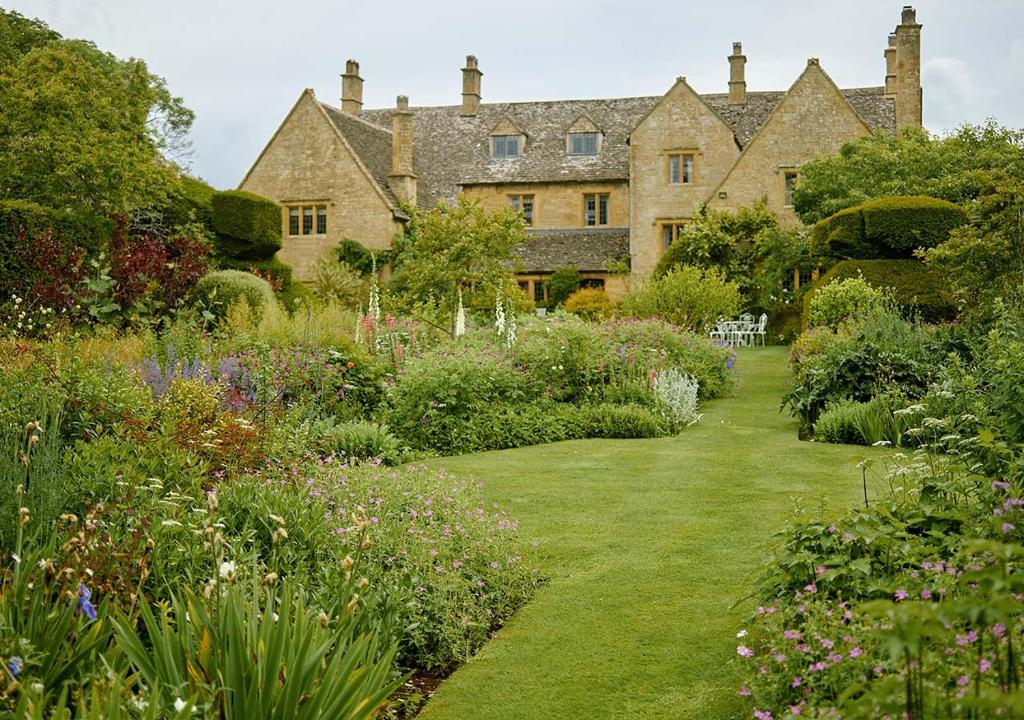 una casa antigua con un jardín delante de ella en Pye Corner a Cotswold Manor with outdoor heated pool, en Broadway