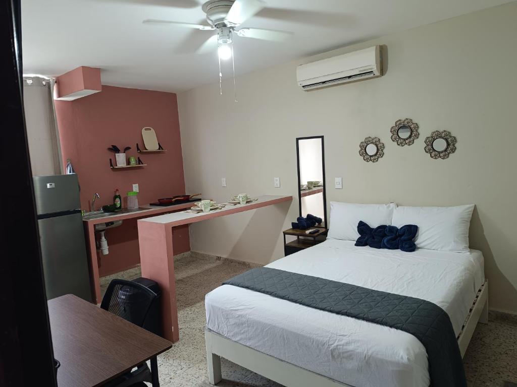 a bedroom with a bed and a desk and a kitchen at Suite 105 Cordoba centro y estacionamiento in Córdoba