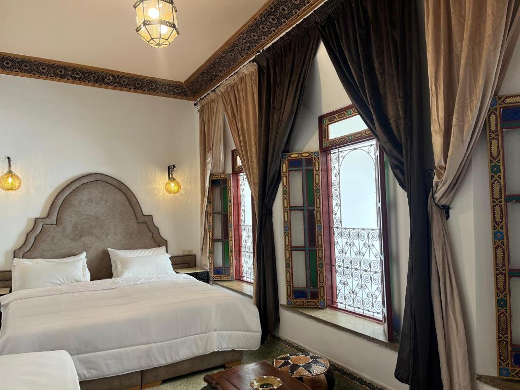 a bedroom with two beds and two windows at Riad Dar Mama Laila in Fès