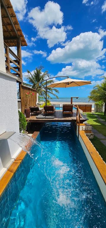 a swimming pool with an umbrella next to a house at Upwind Villas Boutique - Praia de Maceió - Camocim - CE in Maceio