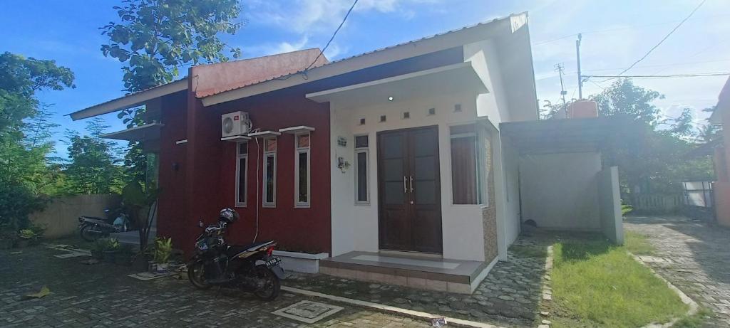 a red and white house with a motorcycle in front of it at Rumah 2 kamar dekat Jl Raya Propinsi in Kebumen