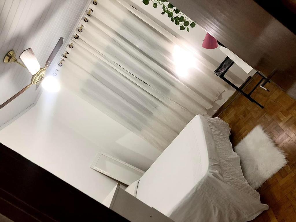 a bedroom with a white bed and a window at Quartos Privados em casa Mobiliada in Londrina