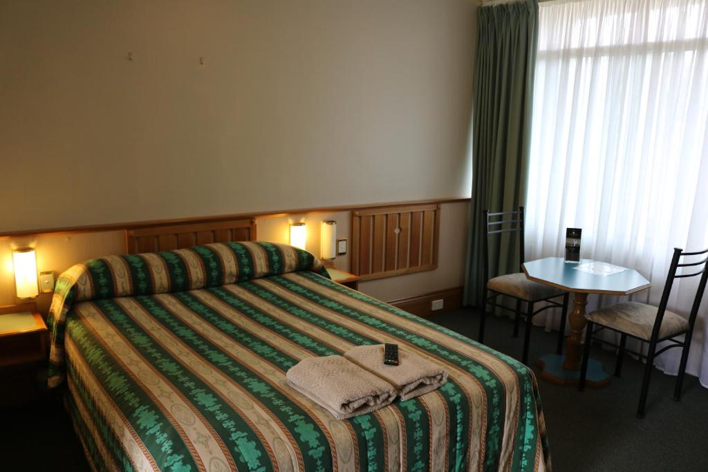 Habitación de hotel con 1 cama con mesa y sillas en Hermitage Motel, en Muswellbrook