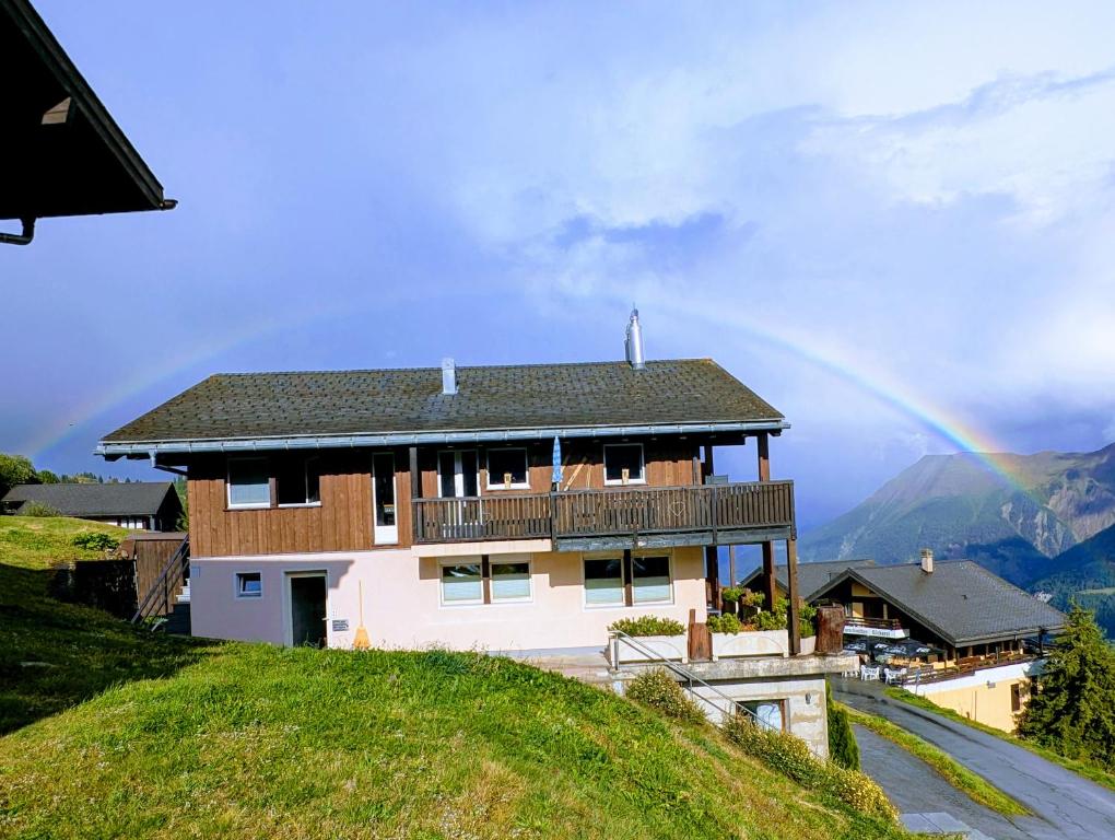a house on a hill with a rainbow in the background at Chalet Talisman auf der Riederalp in Riederalp