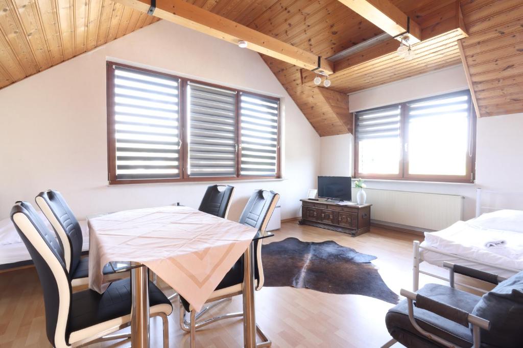 Un comedor con mesa y sillas y ventanas. en La casa de vacaciones-Obermaubach, en Kreuzau