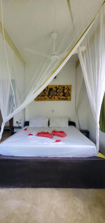 a bedroom with a bed with white sheets and curtains at Nionje Garden Villa in Jambiani