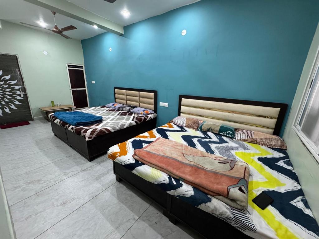 Dos camas en una habitación con paredes azules. en Rudraksh Homestay, en Ujjain