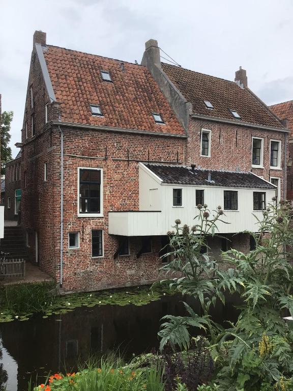 an old brick house with a river in front of it at Solwerderstraat 12 - Hangende Keuken in Appingedam
