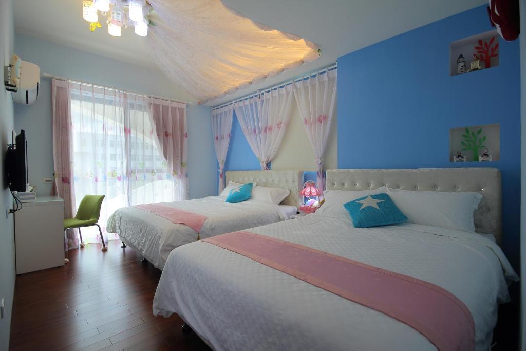 two beds in a bedroom with blue walls at Greek Wonderland B&B in Hualien City