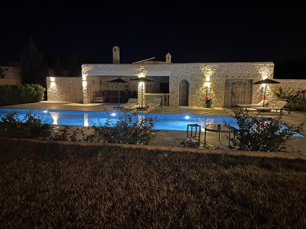 a house with a swimming pool at night at Les Agaves in Oulad el Madani