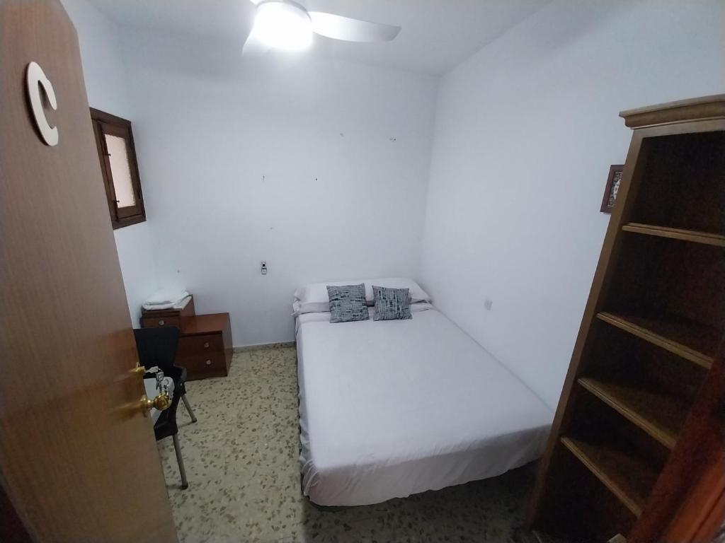 Un pequeño dormitorio con una cama blanca y un armario en Habitación C doble economica, en Cantillana