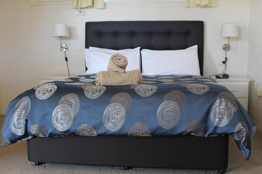 a teddy bear sitting on top of a bed at Cobram Colonial Motor Inn in Cobram