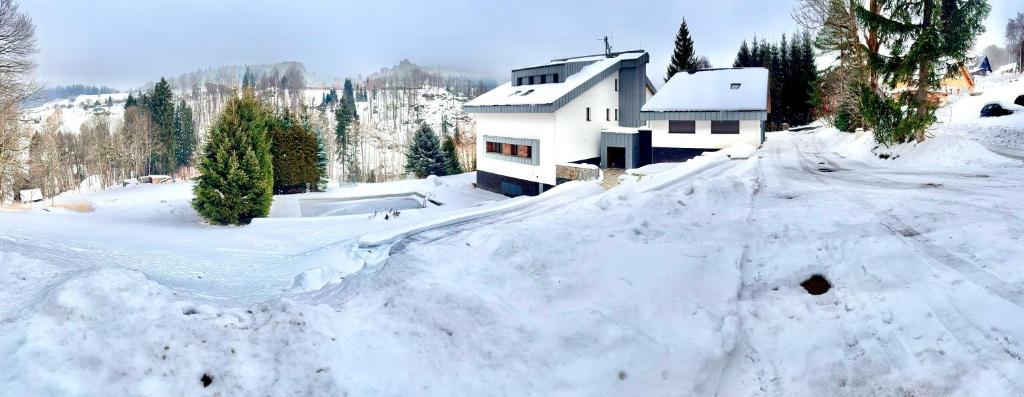 a snow covered yard with a house in the background at Vista 14 in Rokytnice nad Jizerou