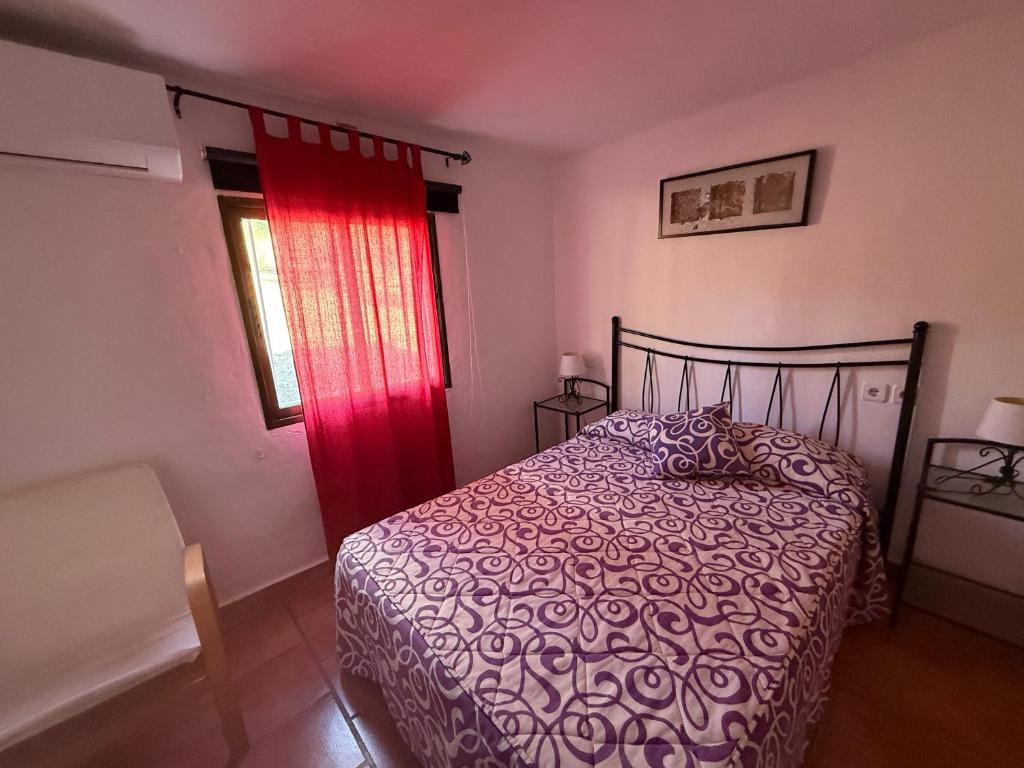 a bedroom with a bed and a red curtain at La Blanca de Aroche in Aroche