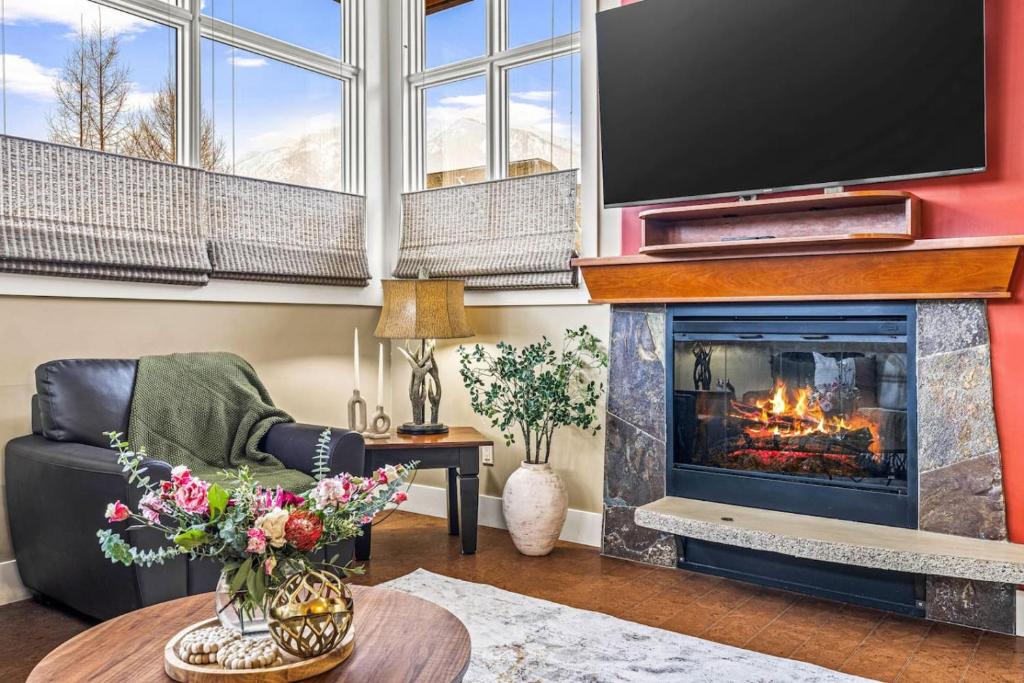 a living room with a fireplace and a flat screen tv at Cozy 2BR Retreat Mountain View with Pool and Hot Tub in Canmore