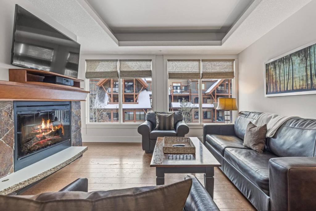 uma sala de estar com um sofá e uma lareira em Mountain View 2BR Condo with Hot Tub, Pool and Gym em Canmore