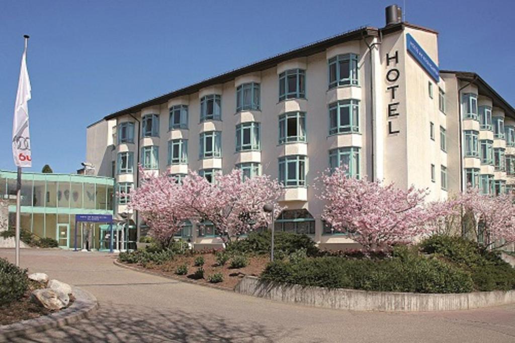 een groot gebouw met roze bloeiende bomen ervoor bij Hotel am Rosengarten in Bad Wimpfen
