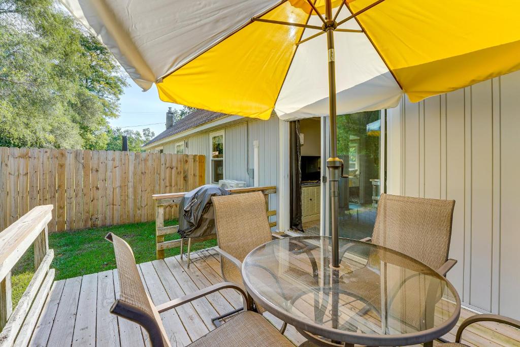 Una mesa de cristal y sillas con una sombrilla en una terraza. en Wayland Retreat with Deck Walk to Downtown!, en Wayland