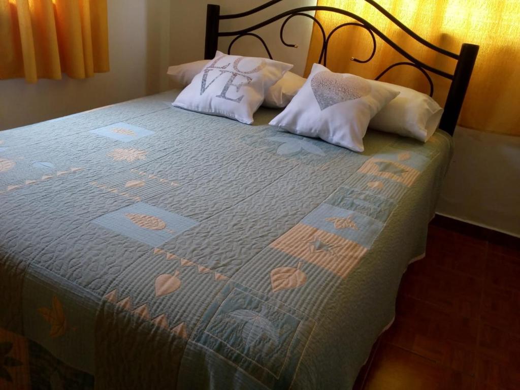 1 cama con 2 almohadas y manta azul en Vicos, en Esquel